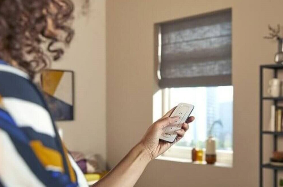 Person controlling motorized shades with a remote